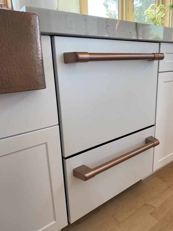 a kitchen with white cabinets and copper handles on the drawers, along with an oven door