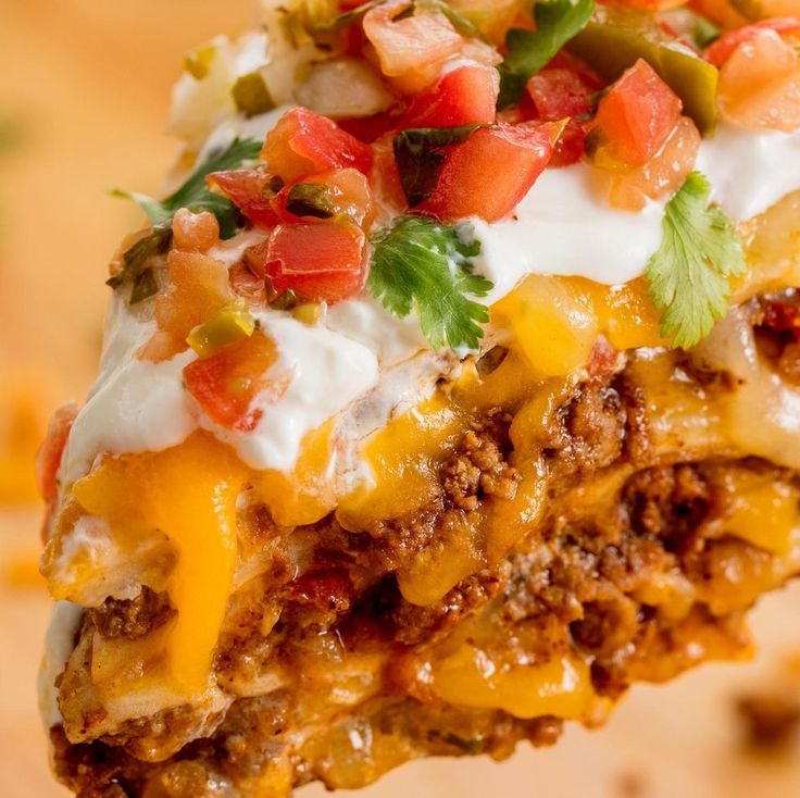 a piece of mexican casserole with sour cream and toppings on the top