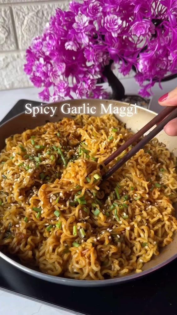 a person holding chopsticks over a bowl of noodles