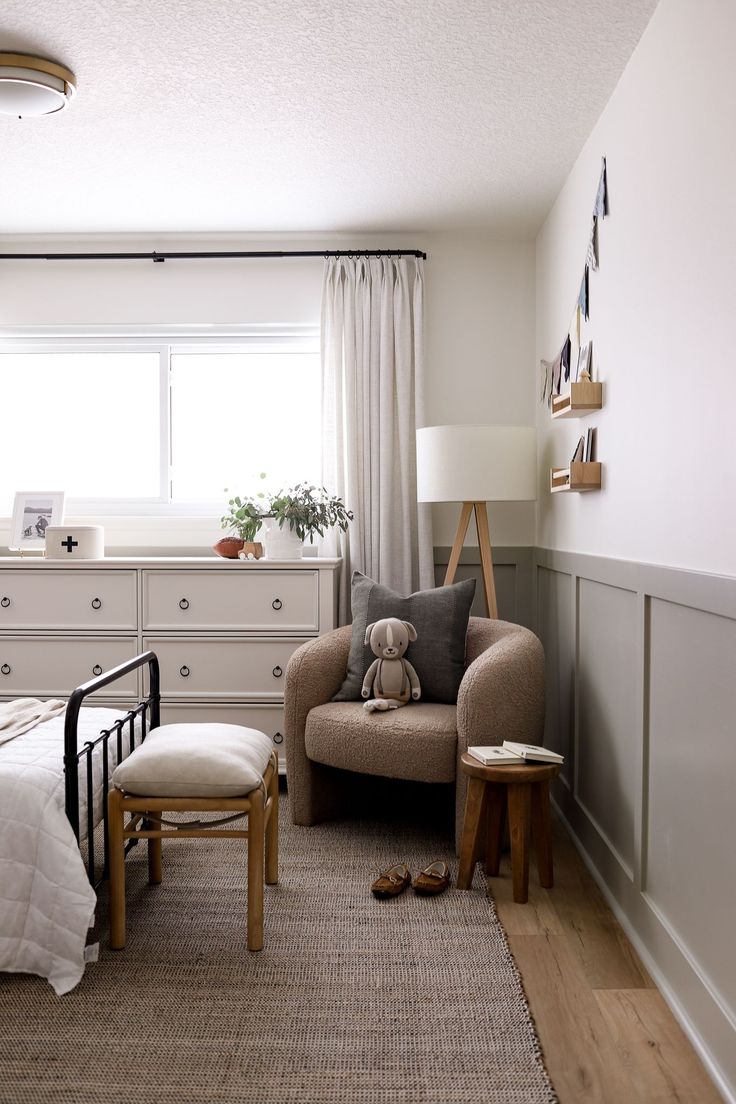 a bedroom with a bed, dresser and chair in it's corner area next to a window