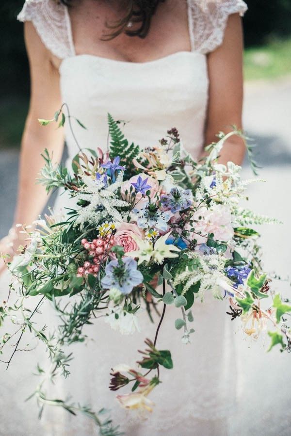 a woman holding a bouquet of flowers in her hands and wearing a white wedding dress