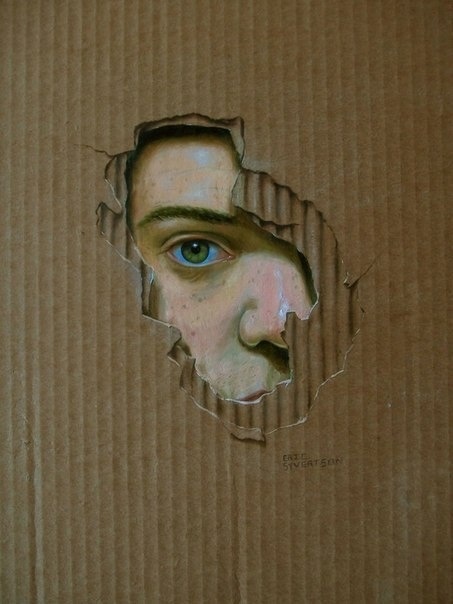 a man's face is seen through a hole in a cardboard box