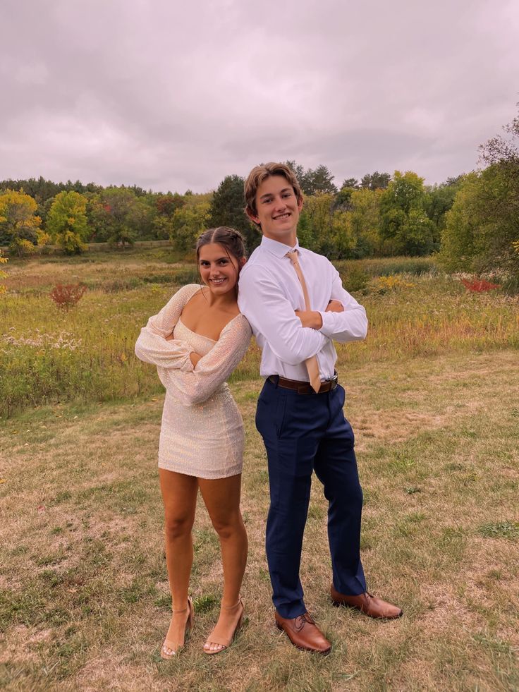 a man and woman posing for a photo in the grass with their arms around each other