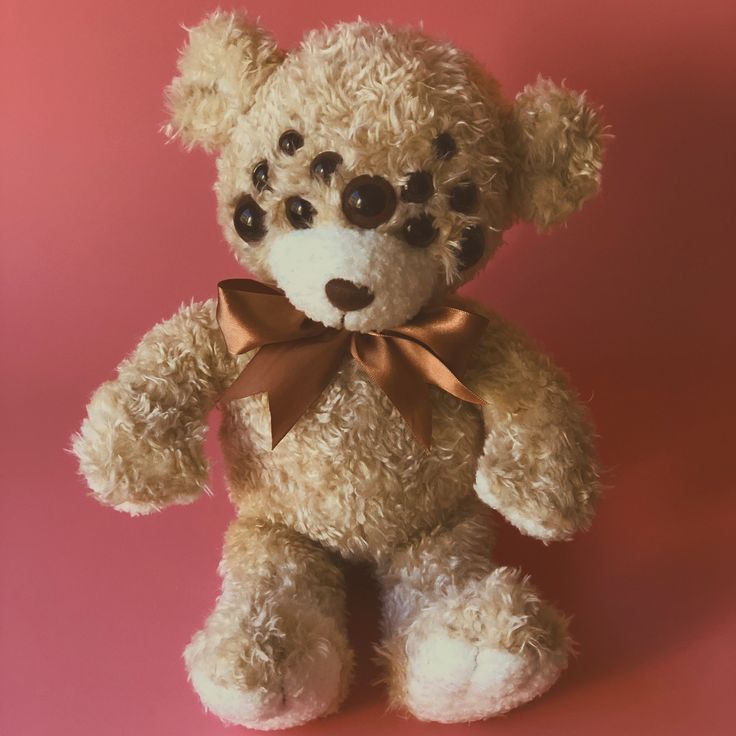 a brown teddy bear with big eyes and a bow