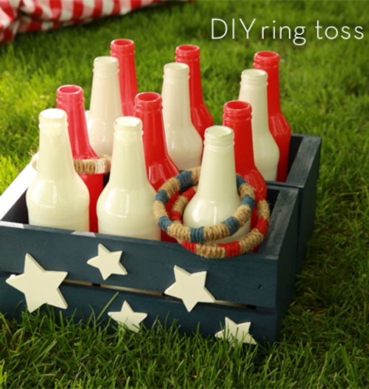 a wooden crate filled with red, white and blue wine bottles sitting on top of green grass