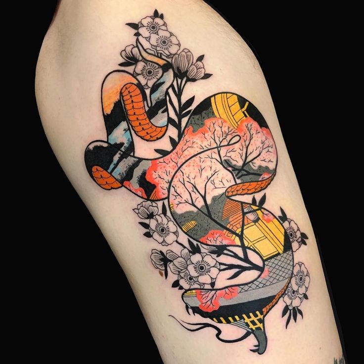 a woman's thigh with an abstract tattoo design on it, including flowers and trees