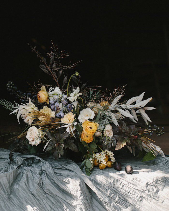 an arrangement of flowers and foliage on a bed