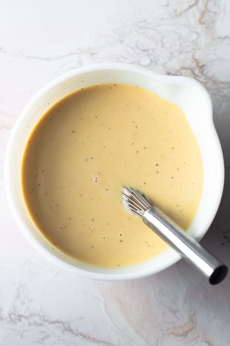 a white bowl filled with soup and a whisk