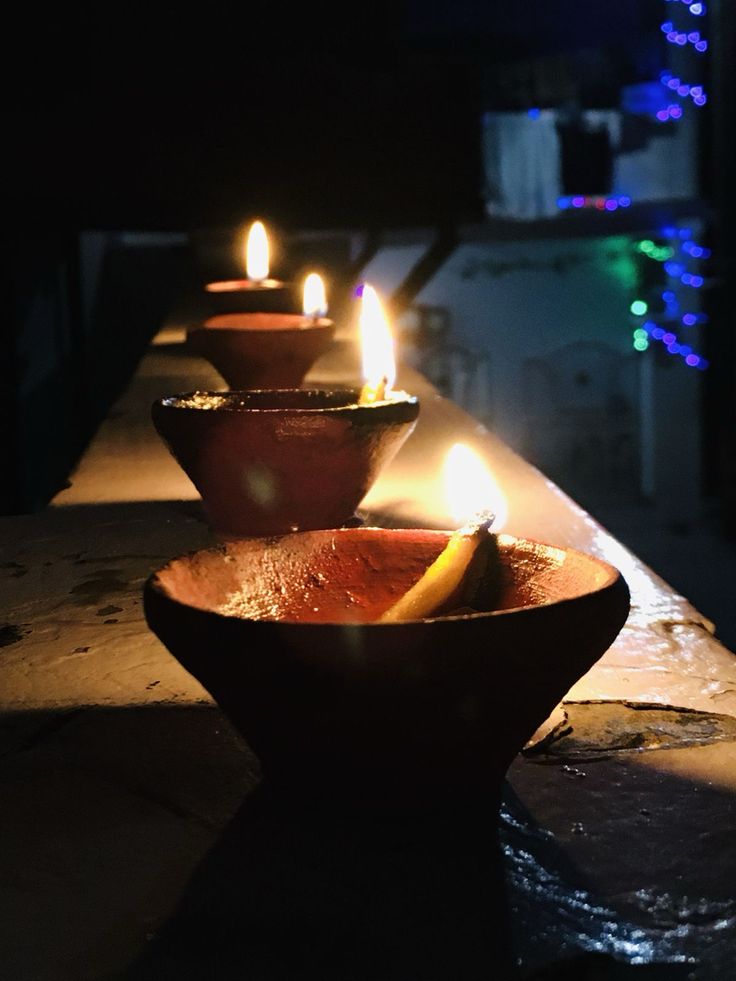 three lit candles sitting on top of a wooden table next to a bowl filled with fruit