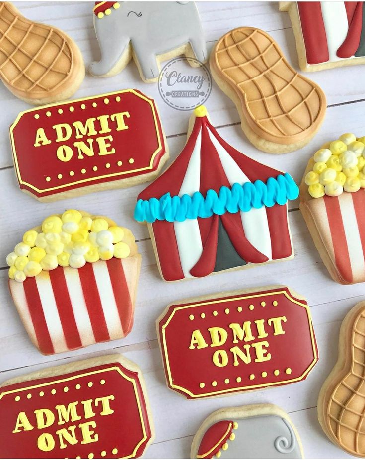 decorated cookies are displayed on a table with red and white striped tent, elephant, movie tickets, and popcorn