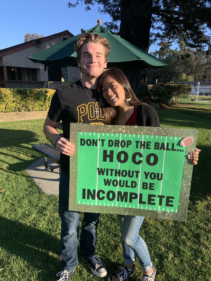 a man and woman holding a sign that says don't drop the ball hoco without you would be incomplete