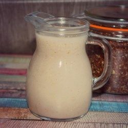 a glass pitcher filled with liquid sitting on top of a wooden table next to jars