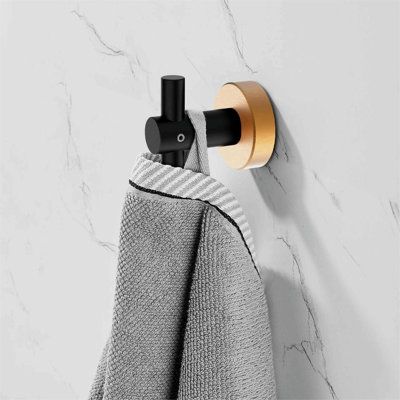 a towel rack with two towels hanging from it's sides, and a gold ring on the wall