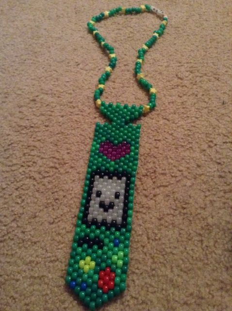 a green beaded necklace with a cat on it