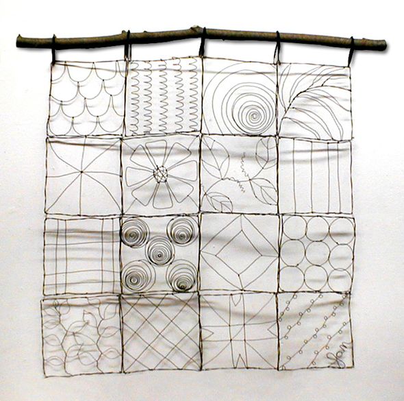 a piece of art made out of wire and paper on a white wall with a bamboo stick in front of it