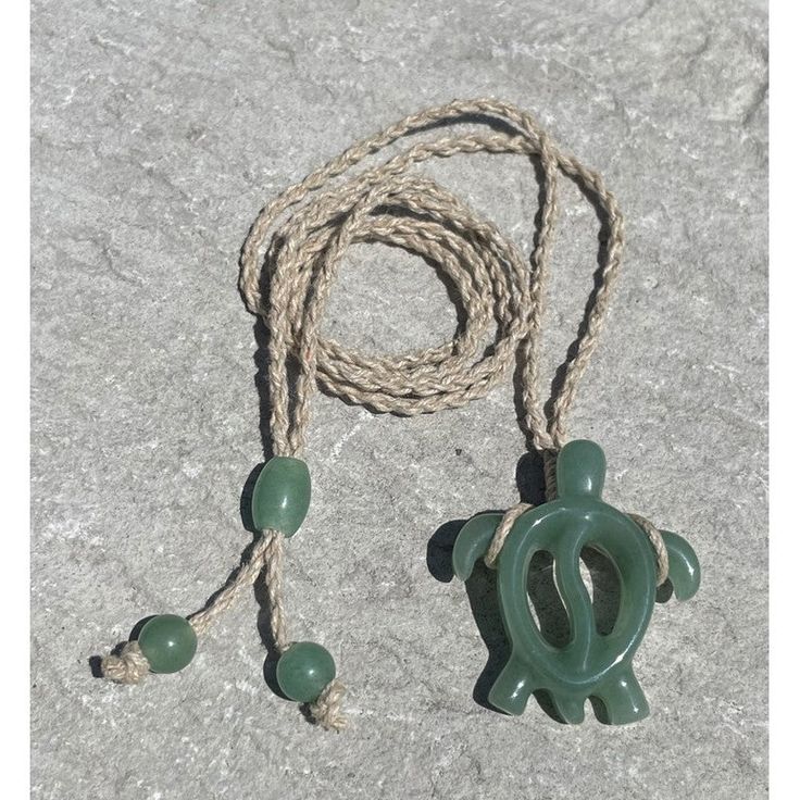 Makana Hut's hand carved Jade Hawaiian Sea Turtle Necklace. This necklace is carved from the beautiful stone Jade which has a green tone and features a natural cotton cord that adjusts to the perfect fit. Honu Turtles or Hawaiian Green Sea Turtle is the only indigenous reptile found in Hawaii. Known in Hawaiian as “Honu,” the turtle symbolizes good luck, endurance and long life. Turtles represent the navigator and are a link between people, the land and the sea. Hawaiian Sea Turtle (HONU): Symbo Carved Pendant Jewelry, Artisan Jewelry With Adjustable Cord In Natural Color, Artisan Carved Adjustable Jewelry, Traditional Jewelry With Sliding Knot For The Beach, Handmade Casual Jade Jewelry, Handmade Cord Jewelry For The Beach, Artisan Adjustable Natural Color Necklaces, Artisan Adjustable Natural Necklaces, Casual Green Adjustable Necklace