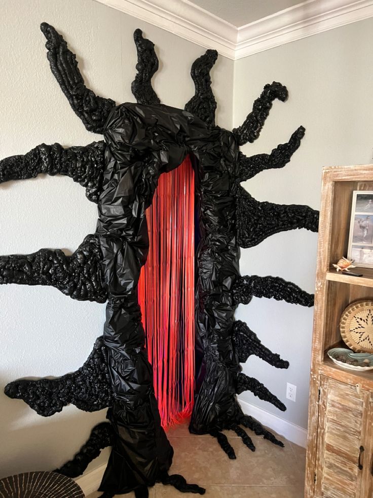 a sculpture made out of black plastic and red string hanging from it's sides