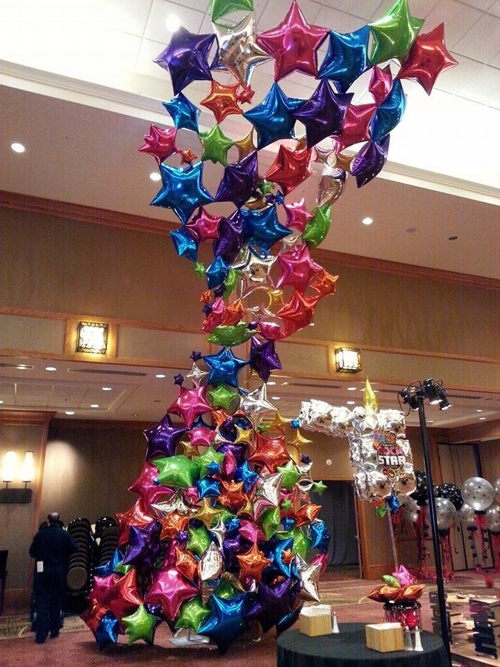 a very colorful christmas tree made out of many different colored balloons and bows on it