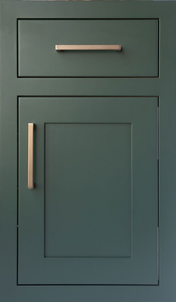 a green cabinet door with brass handles and knobs on the bottom, against a blue wall