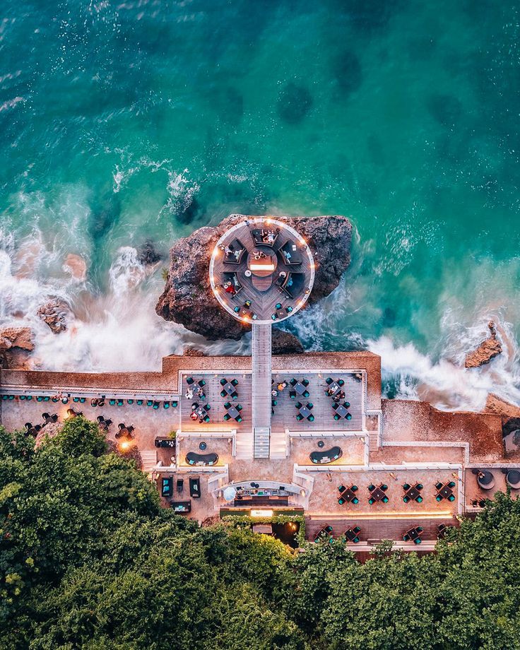 an aerial view of the ocean and beach with tables set up on top of it