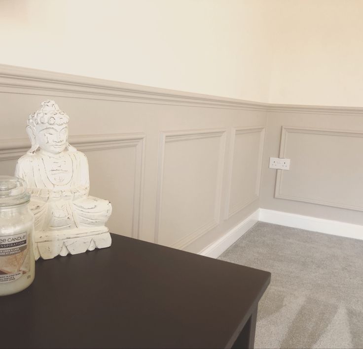 a white buddha statue sitting on top of a table next to a jar of candles