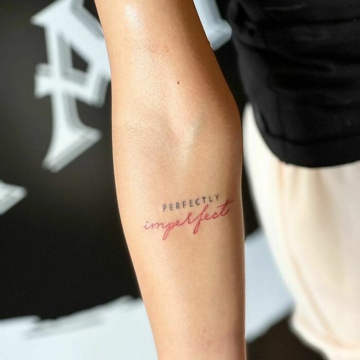 a woman's arm with the word perfectly imperfect written on it in cursive writing