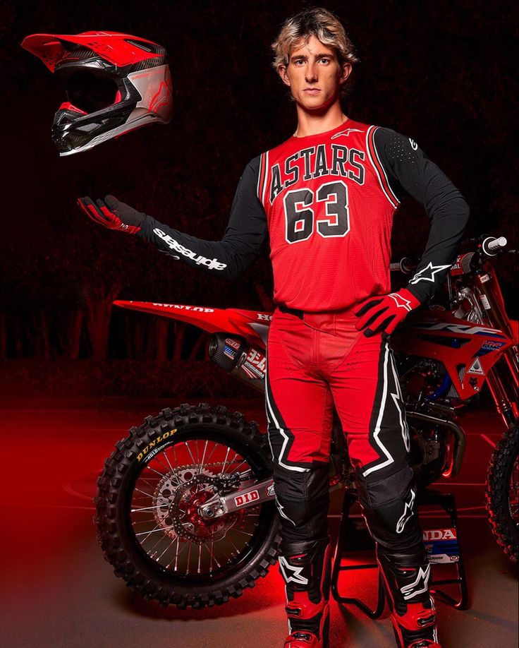 a man standing next to a dirt bike on a red and black background with the words acumen limited written below him