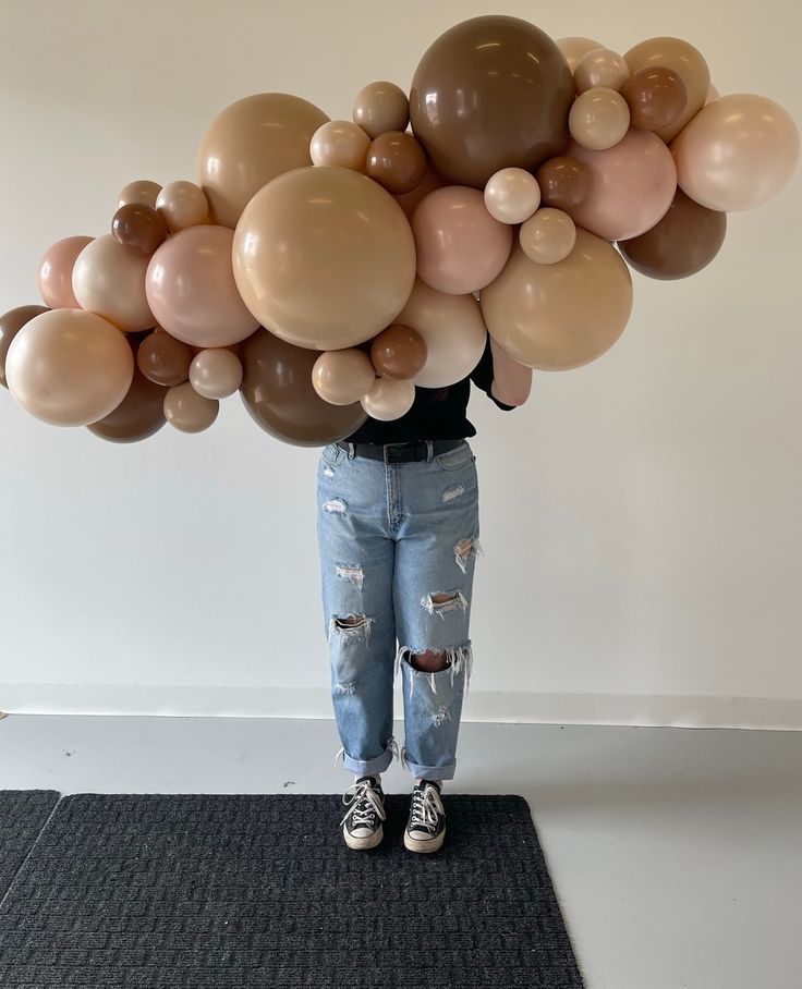 a person standing on a rug with balloons in the shape of an arch over their head