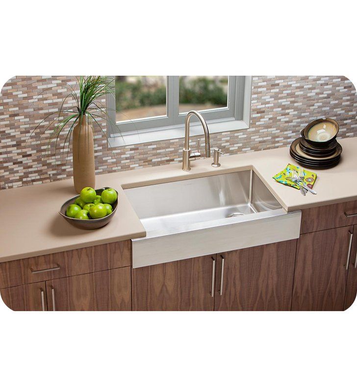 a kitchen sink sitting under a window next to a bowl of green apples and a vase