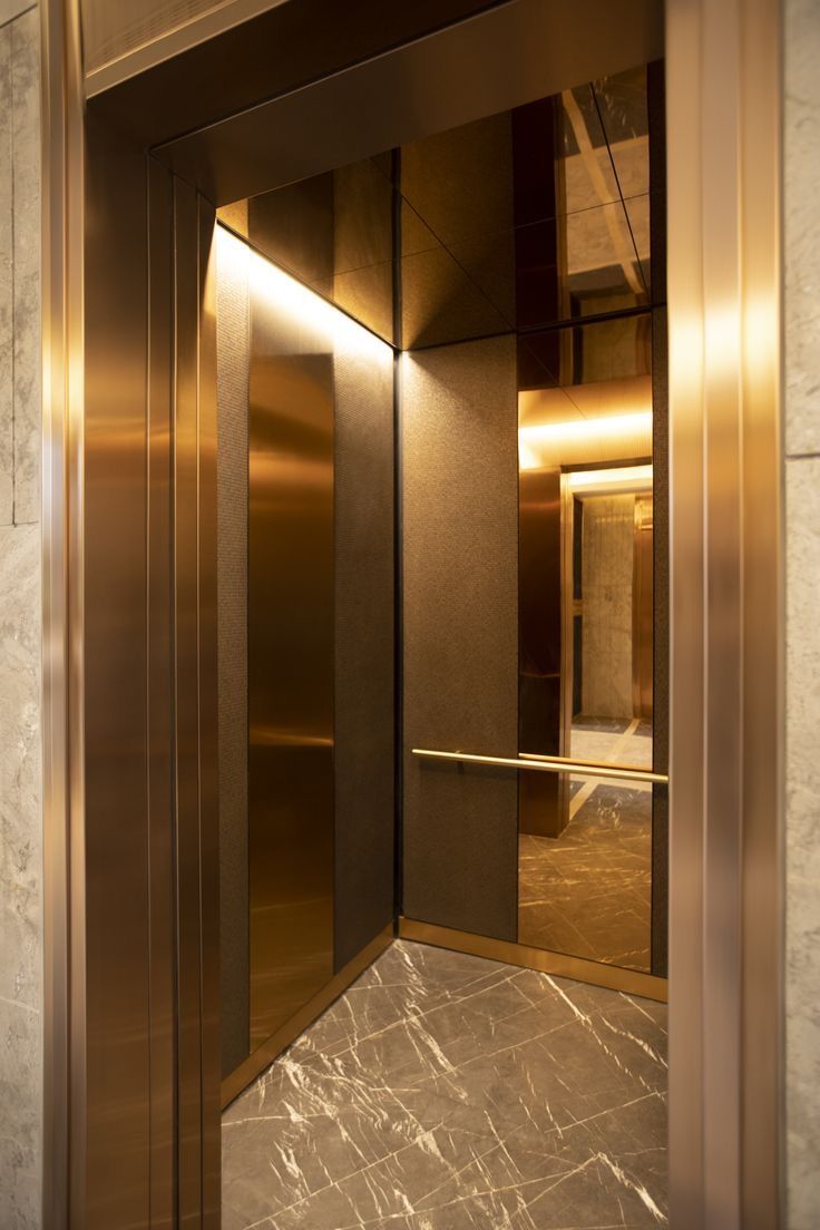 an open elevator door in a building with marble flooring and gold trimmings