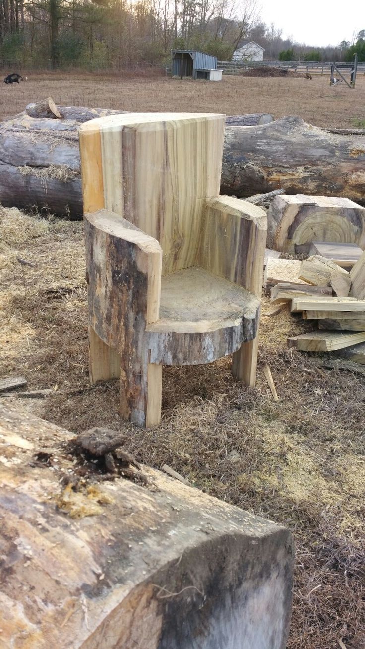 a chair made out of wood sitting on top of a pile of tree stumps