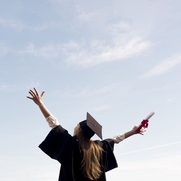 a woman wearing a graduation cap and gown holding her arms in the air