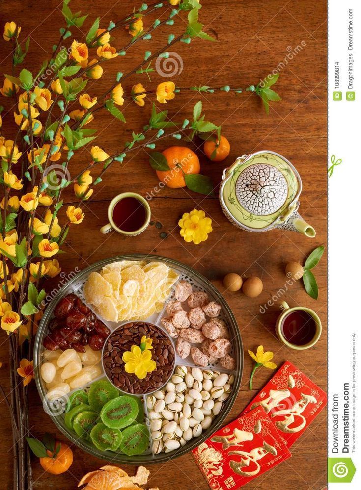 an assortment of chinese food on a plate with flowers and teapots in the background