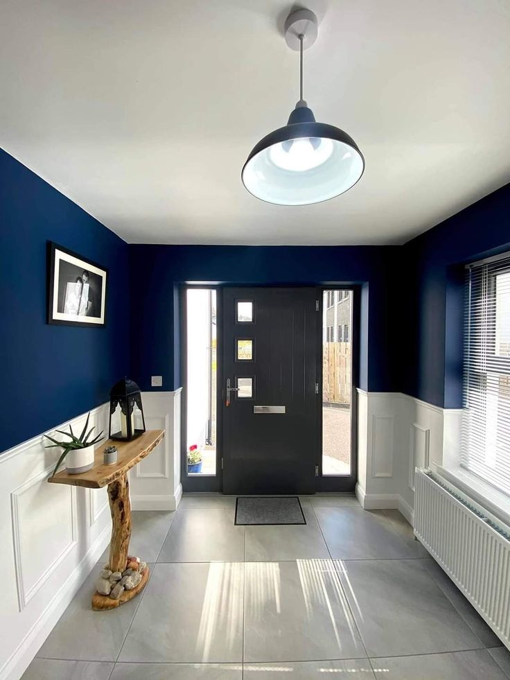 an empty hallway with blue walls and white trim on the doors, windows, and table