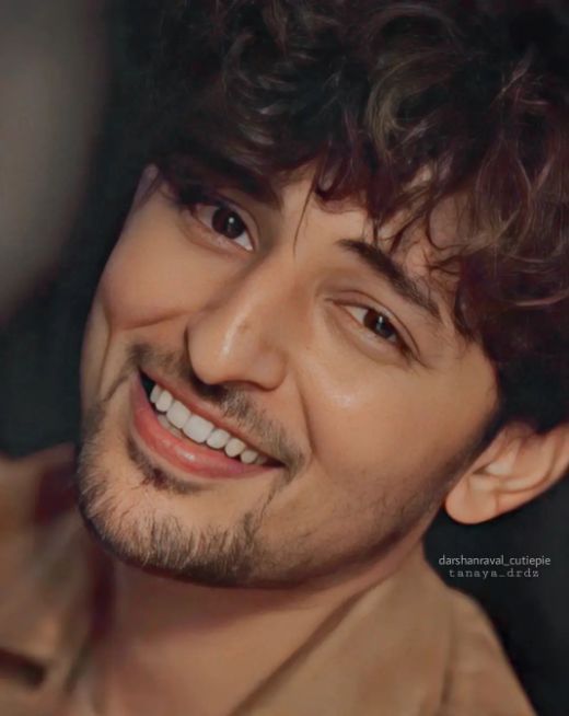 a man with curly hair smiling at the camera