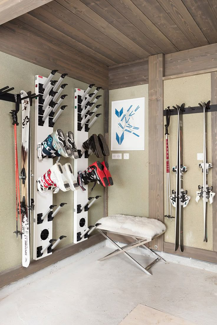 a room with skis and snowboards on the wall, along with a bench