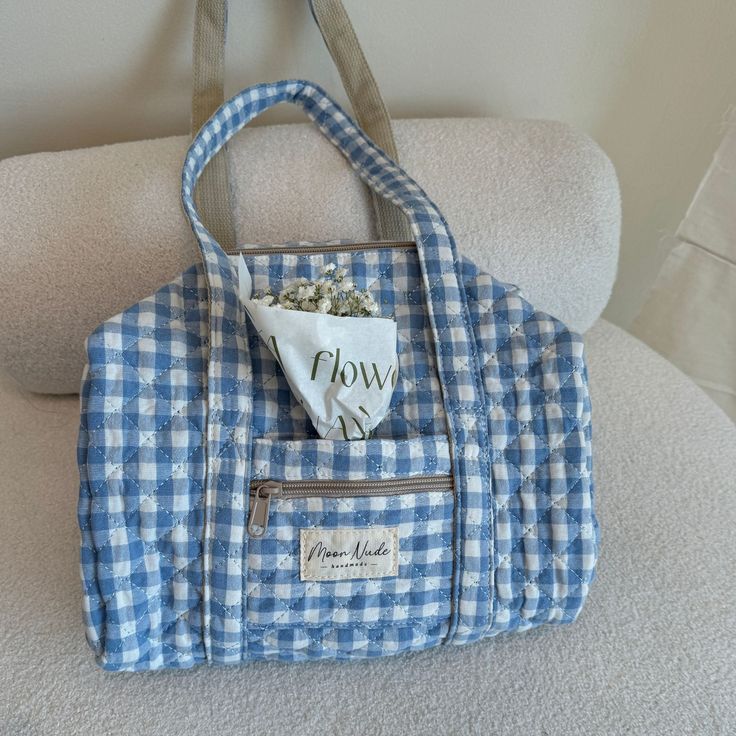 Discover elegance in compact form with our Azure Mini Duffel Bag, a stylish carry-all with a convenient zippable front pocket,  crafted to be your perfect companion for impromptu outings or as a sleek organizer for your essentials.    The quilted exterior is made from a beautiful blue gingham material, complemented by a matching gingham interior.   From gym sessions to weekend getaways or daily errands, this mini duffel effortlessly blends organization with style, offering a chic solution for yo Quilted Double Handle Shoulder Bag For Daily Use, Quilted Shoulder Bag With Double Handle For Daily Use, Weekend Rectangular Bag With Zipper Pocket, Weekend Rectangular Shoulder Bag With Zipper Pocket, Rectangular Bags With Zipper Pocket For Weekend, Quilted Double Handle Bag For Everyday, Quilted Shoulder Bag For Everyday Use, Everyday Quilted Satchel Bag, Everyday Quilted Satchel Shoulder Bag