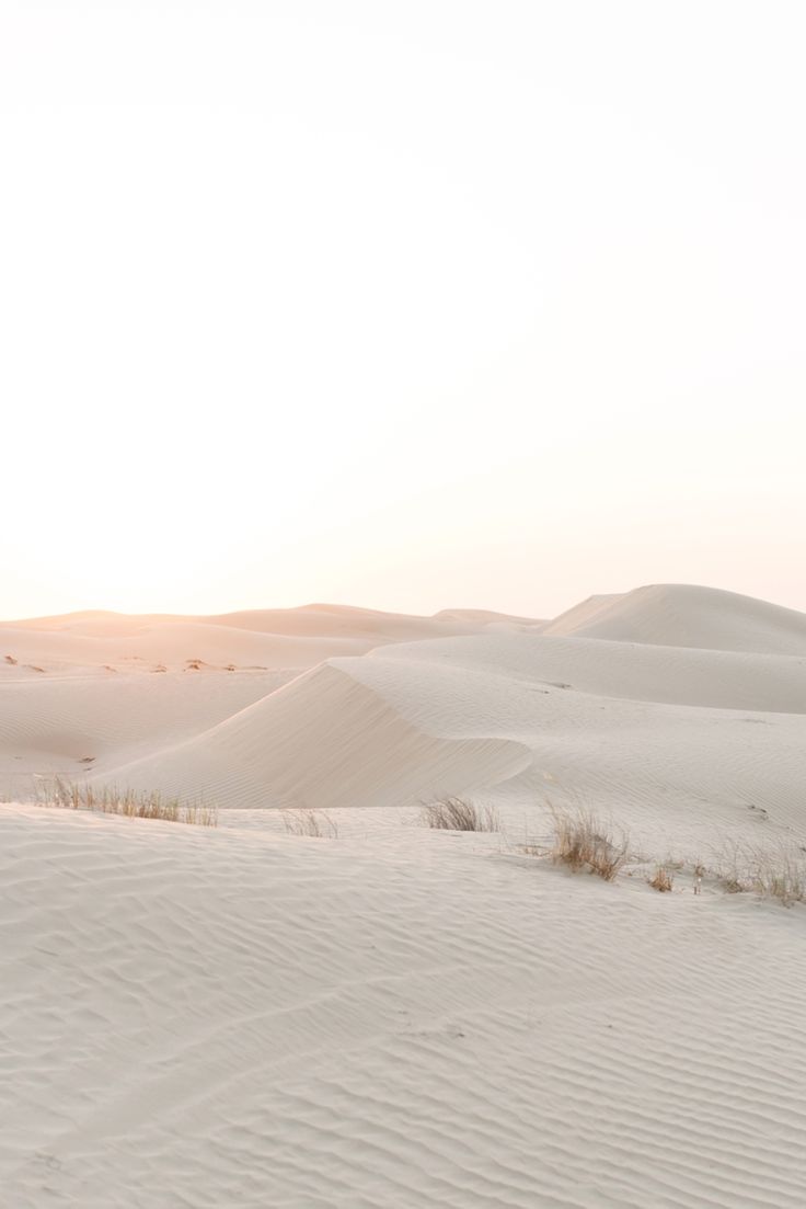 the sun is setting over sand dunes in the desert