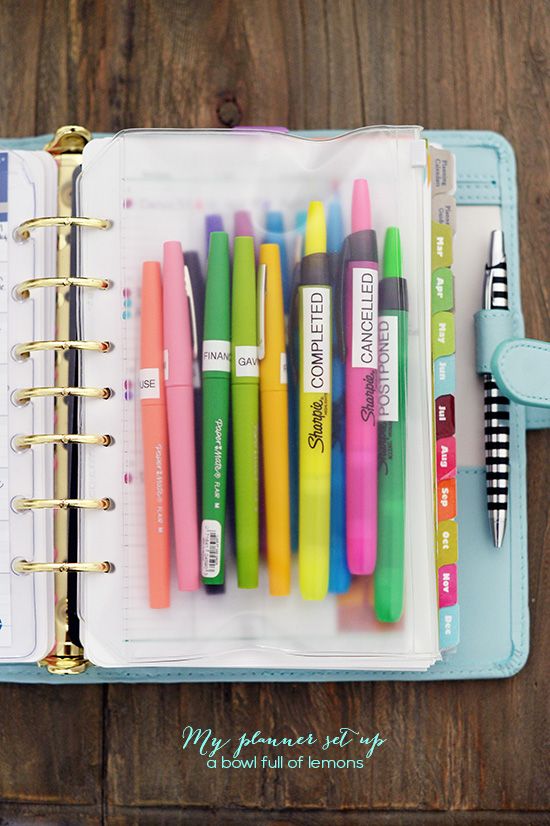 an open planner with pens in it on a wooden table