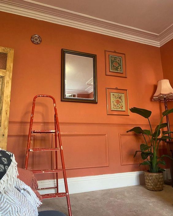 a living room with orange walls and pictures on the wall, including a red ladder