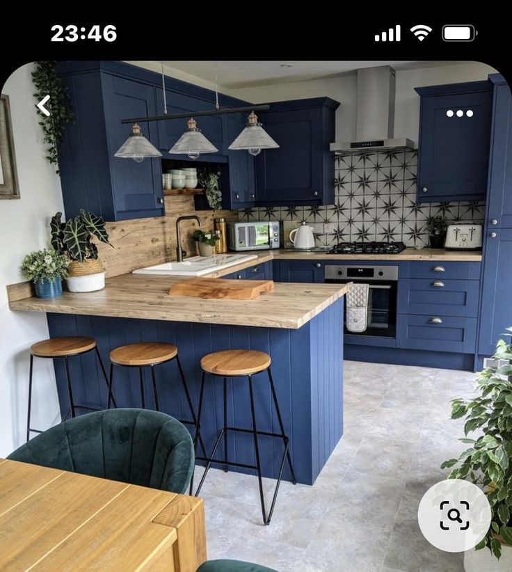 a kitchen with blue cabinets and stools in front of an island counter top, surrounded by potted plants