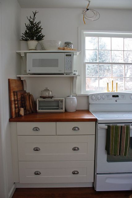 a white stove top oven sitting inside of a kitchen next to a microwave and window