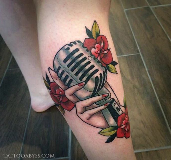 a woman's leg with a microphone and flowers tattoo on her legs, while she is holding the mic