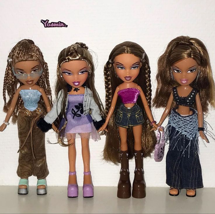 three dolls are standing next to each other in front of a white wall and one is holding a purse