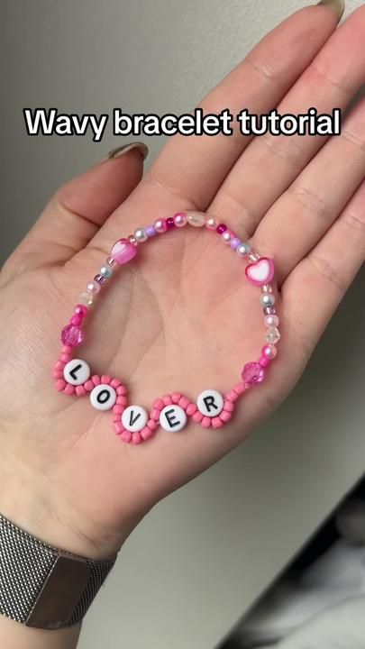 a woman's hand holding a pink beaded bracelet with words written on it