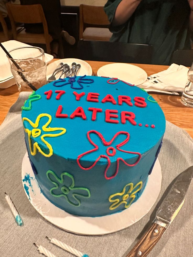 a blue birthday cake sitting on top of a table next to silverware and utensils