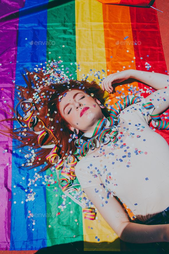 a woman laying on top of a rainbow colored blanket