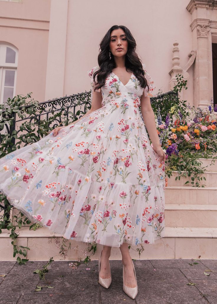 Happily Ever After Our best-selling Jeanne Dress is making her spring debut in a beautiful bight white color with one of a kind floral embroidery. This is a dress designed for the girl who loves to stand out. A slight open back completes the look with feminine charm. V neckline Sleeveless Empire waist Back zipper Runs V-neck Embroidered Maxi Dress For Summer, White V-neck Dress With Floral Embroidery, Spring Floral Embroidered A-line Maxi Dress, Feminine Floral Embroidered Dress For Garden Party, Spring Floral Print V-neck Sundress, Feminine Long Floral Dress For Garden Party, Feminine Floral Dress For Garden Party, Summer Party Maxi Dress With Floral Applique, Spring Garden Party V-neck Maxi Dress