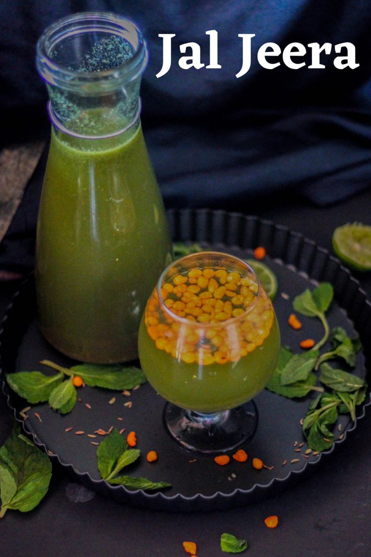 a green smoothie in a glass next to a bottle of juice and some leaves