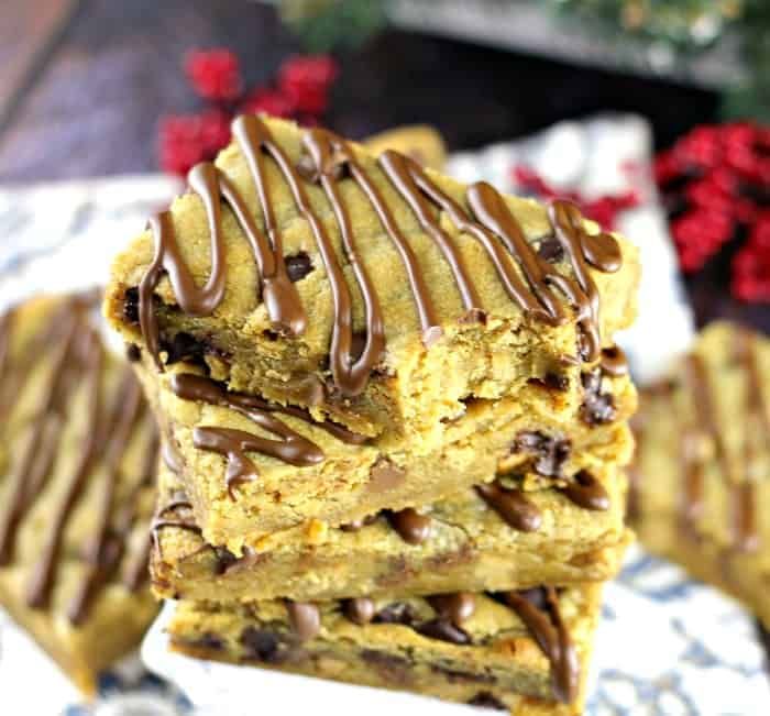 a stack of dessert bars with chocolate drizzled on top, sitting on a plate